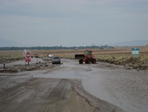 A loader works to clear water and mud from U.S. 395 near Independence in July, 2008.