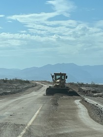 A grader pushes mud off State Route 190 in Death Valley National Park following historic flooding in August, 2022.