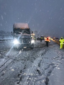 Snow continues to fall into the evening as Caltrans crews and emergency responders attend to a jackknifed big rig on State Route 58 in December, 2021.