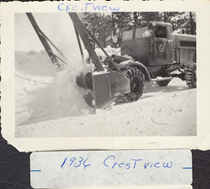 A black and white image of an old snowblower clearing snow from the road in 1936. Writing on the picture reads "Crestview. 1936 Crestview."