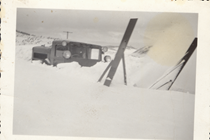 An undated black and white image of a snowblower clearing snow from the highway. The snow is so deep nothing on the vehicle below the cab is visible.