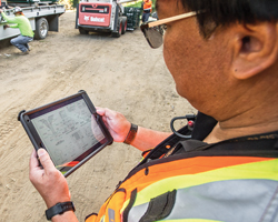 A Caltrans transportation engineer inspects a handheld tablet at a job site