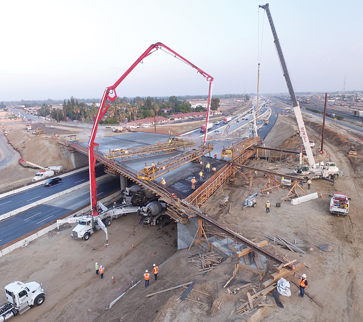 Aerial photo of workers and a crane lifting materials during construction of new overpass